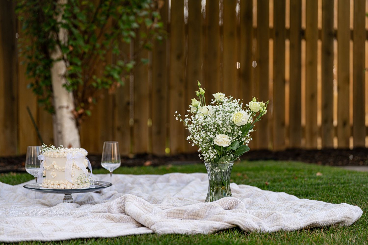 Wedding cake and floral decorations displayed in an outdoor garden setting.