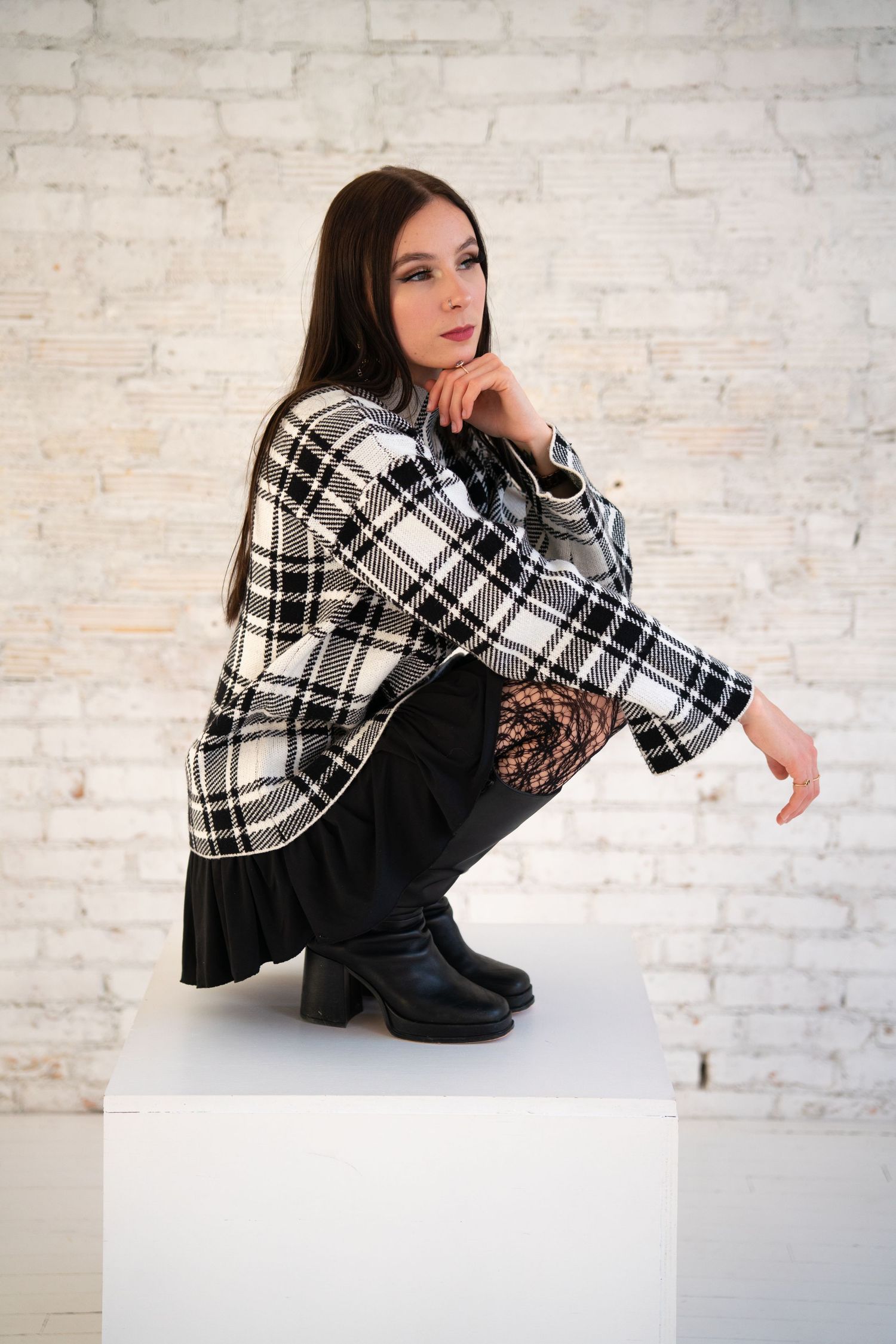 Fashion photo shoot against white brick wall featuring black and white plaid clothing.