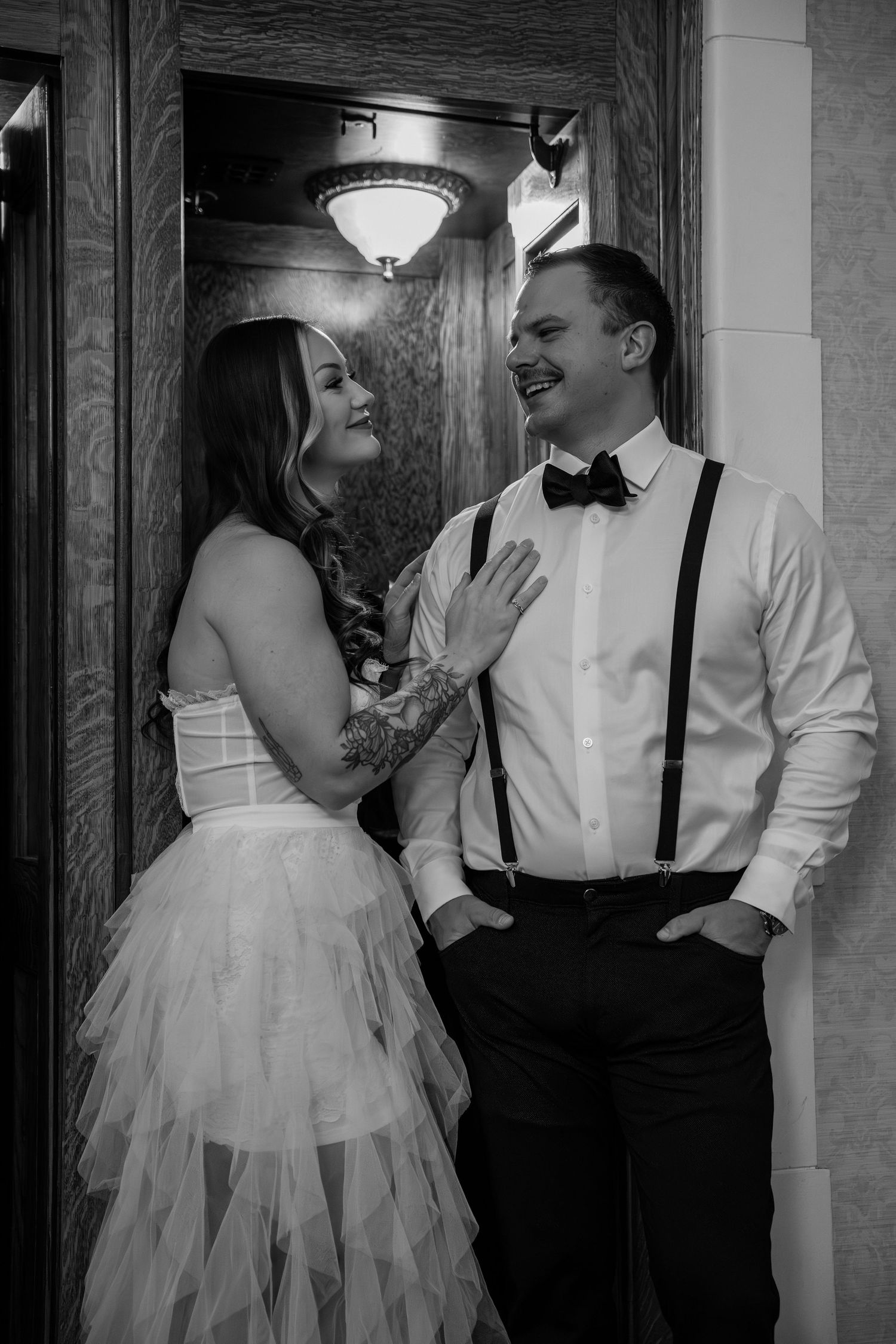 Romantic black and white portraits of wedding couple laughing together in vintage hallway.