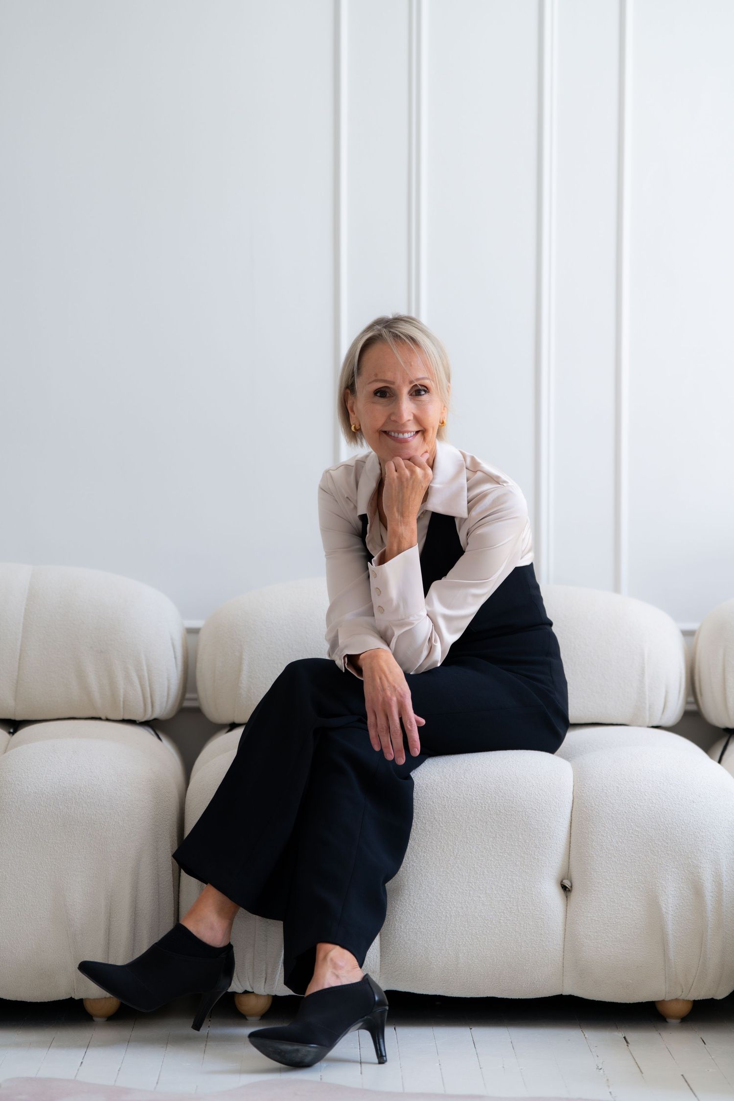 Professional photo series showing someone in business attire posing on a white sofa.