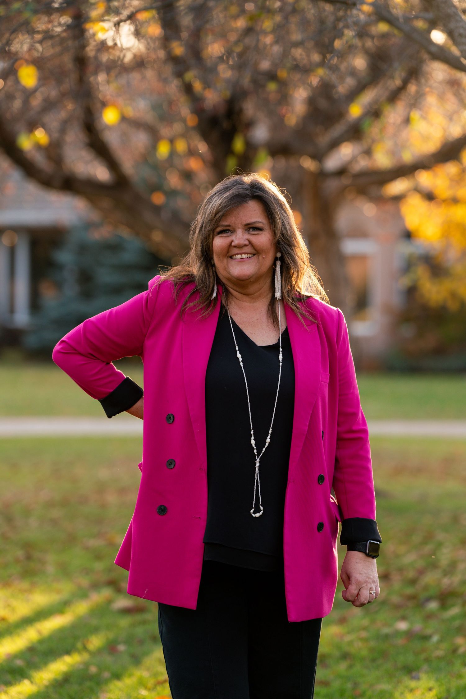 Outdoor autumn photoshoot featuring someone in a bright pink blazer and black dress.