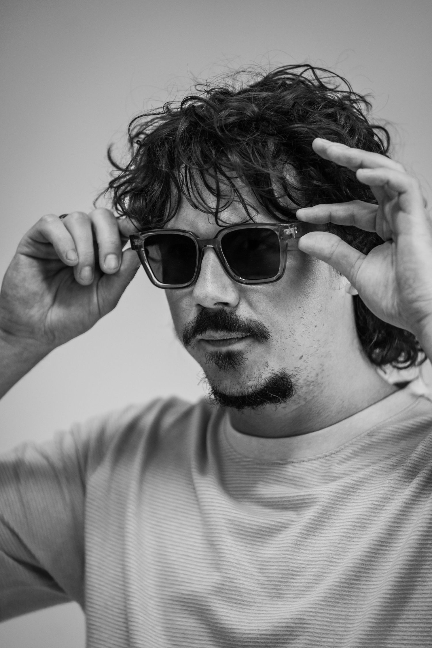 Black and white portrait series showing someone adjusting sunglasses.