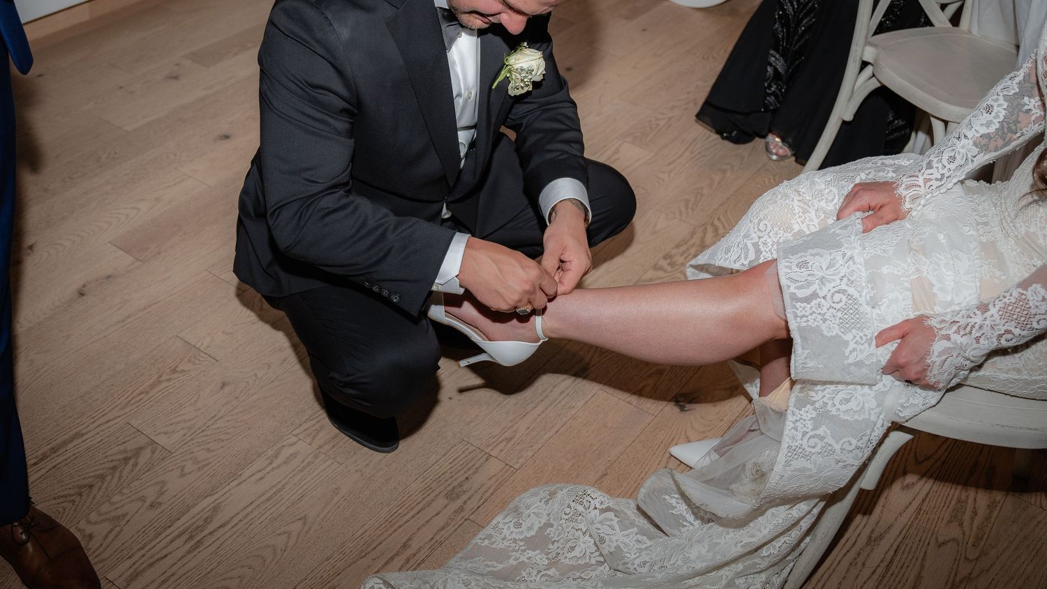 Close-up shot of wedding garter tradition being performed on wooden floor.