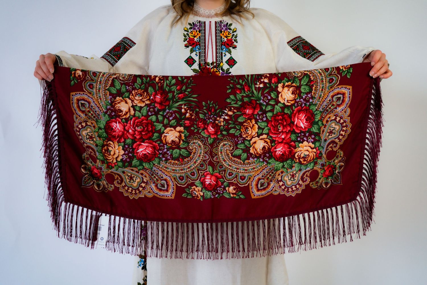 Traditional red shawl with intricate floral embroidery and fringe detail.