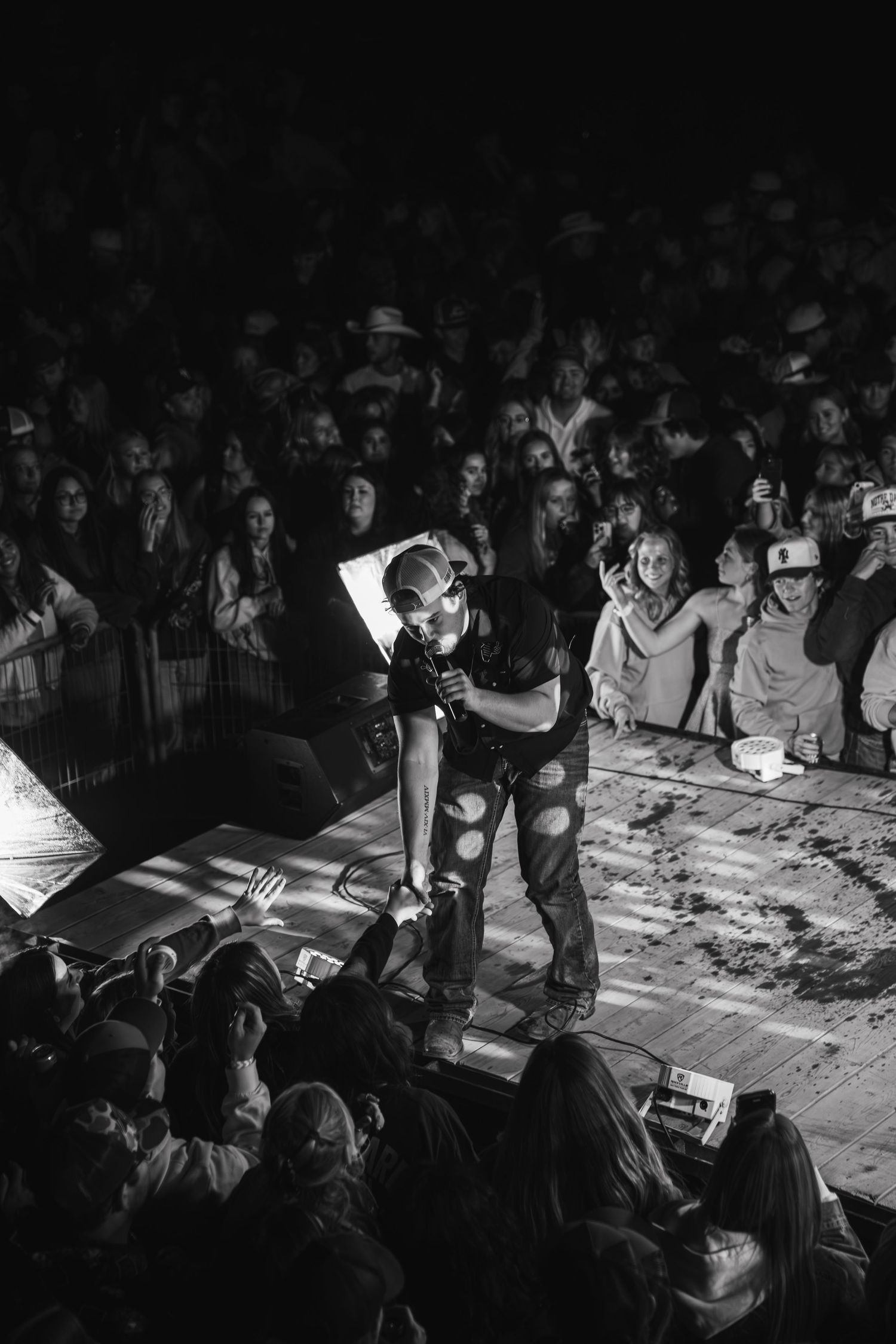 Black and white photo of a crowded audience gathered around a table in a dimly lit room.