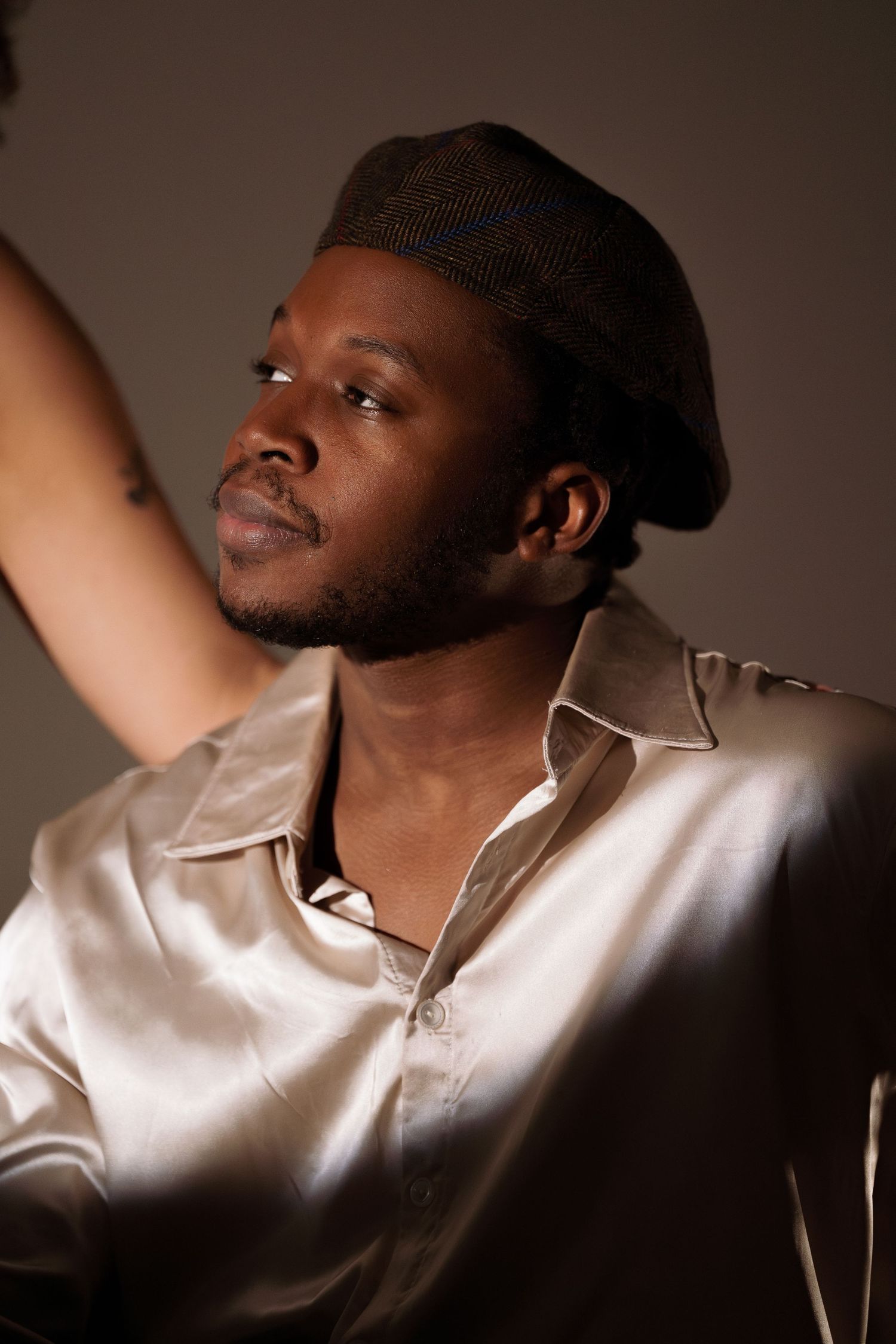 Studio portraits with dramatic lighting showing person in white polo and cap.