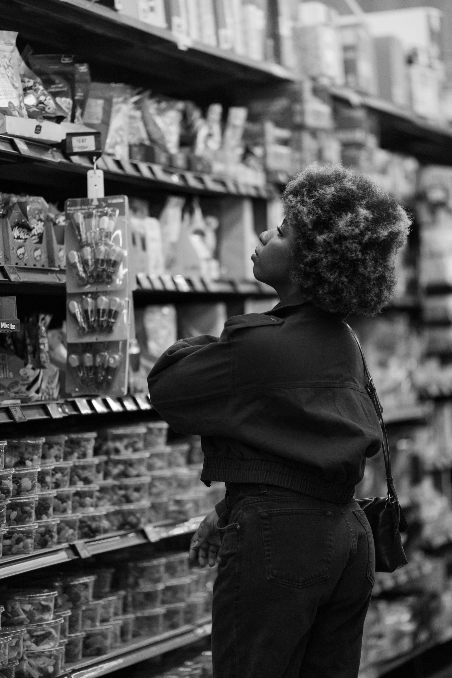 Shopper browsing grocery store shelves in vintage black and white photograph.