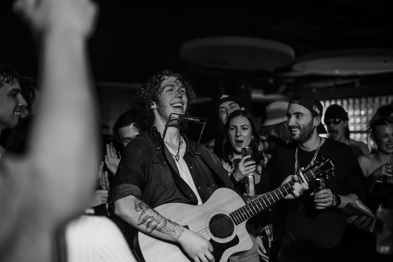 Concert crowd enjoying live music performance in a dark venue with dramatic lighting.