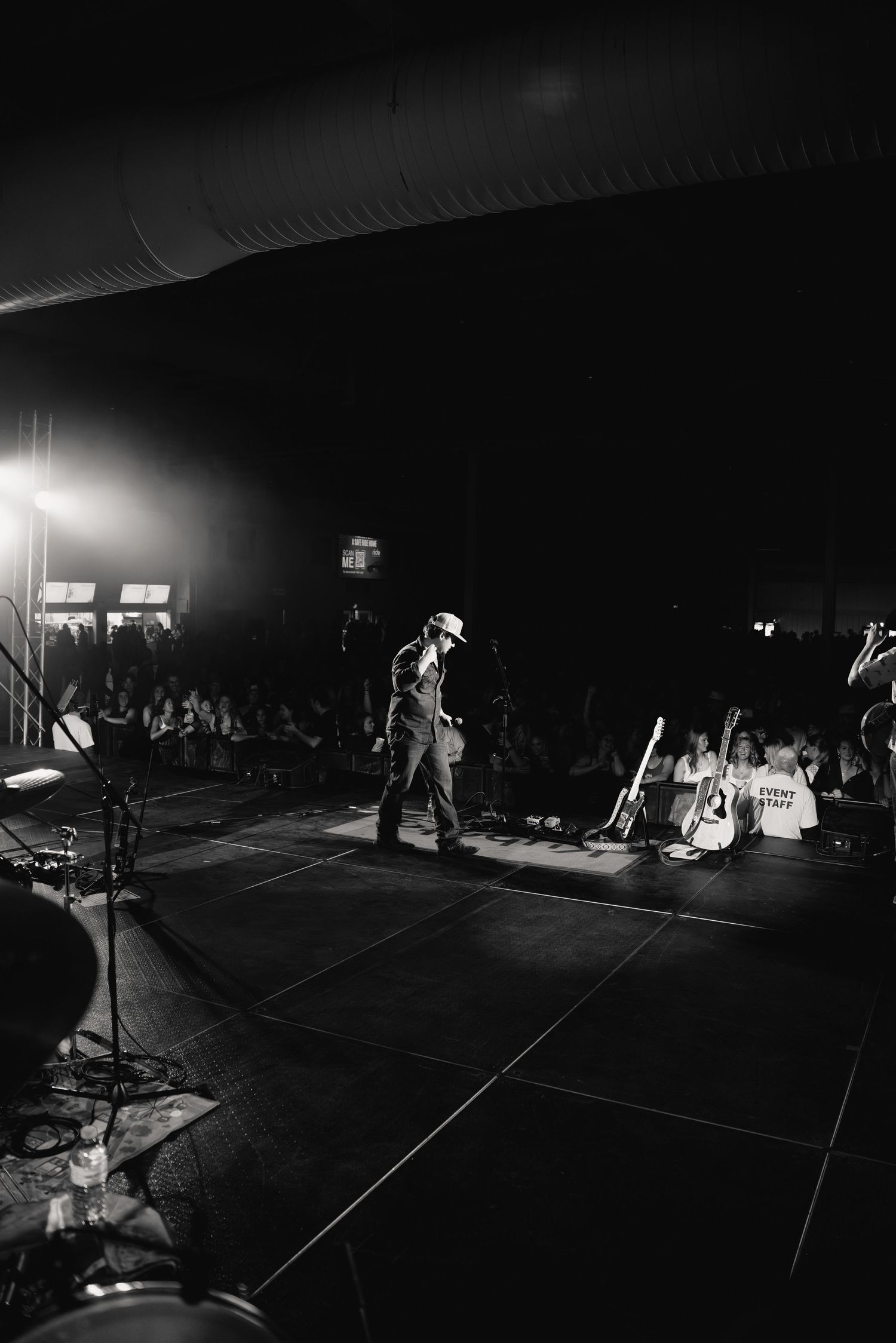 Dark performance space with silhouettes and stage lighting creating dramatic atmosphere.