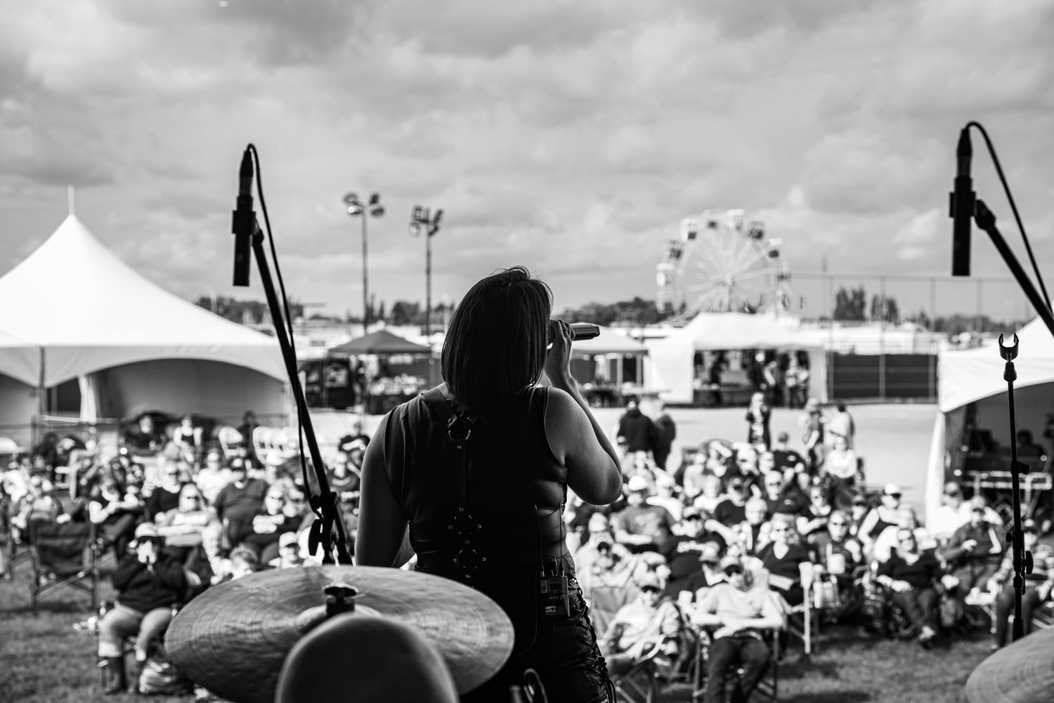 Outdoor festival with white tents and a ferris wheel visible in the background.