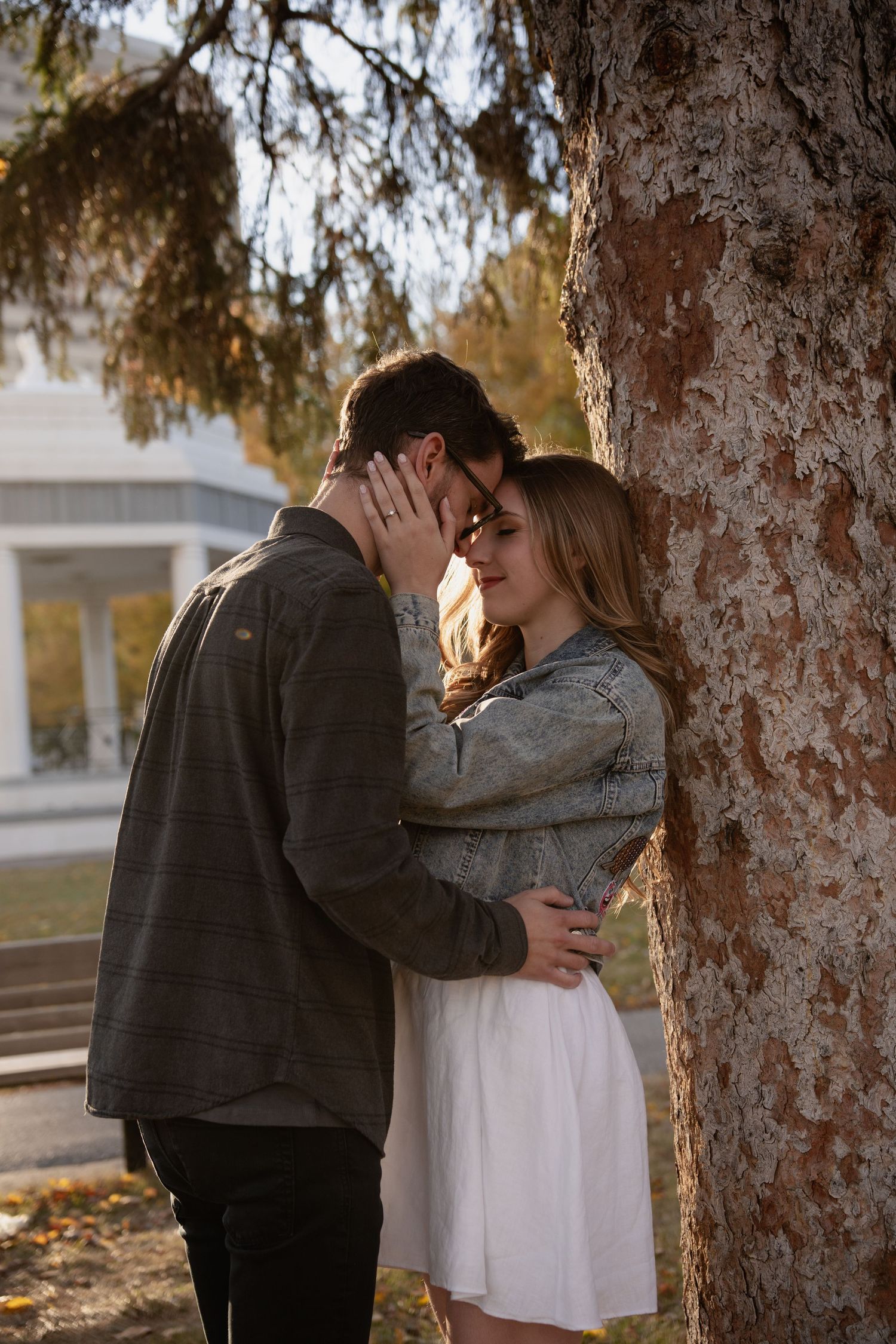 Intimate couple portraits against textured tree bark in warm autumn light.