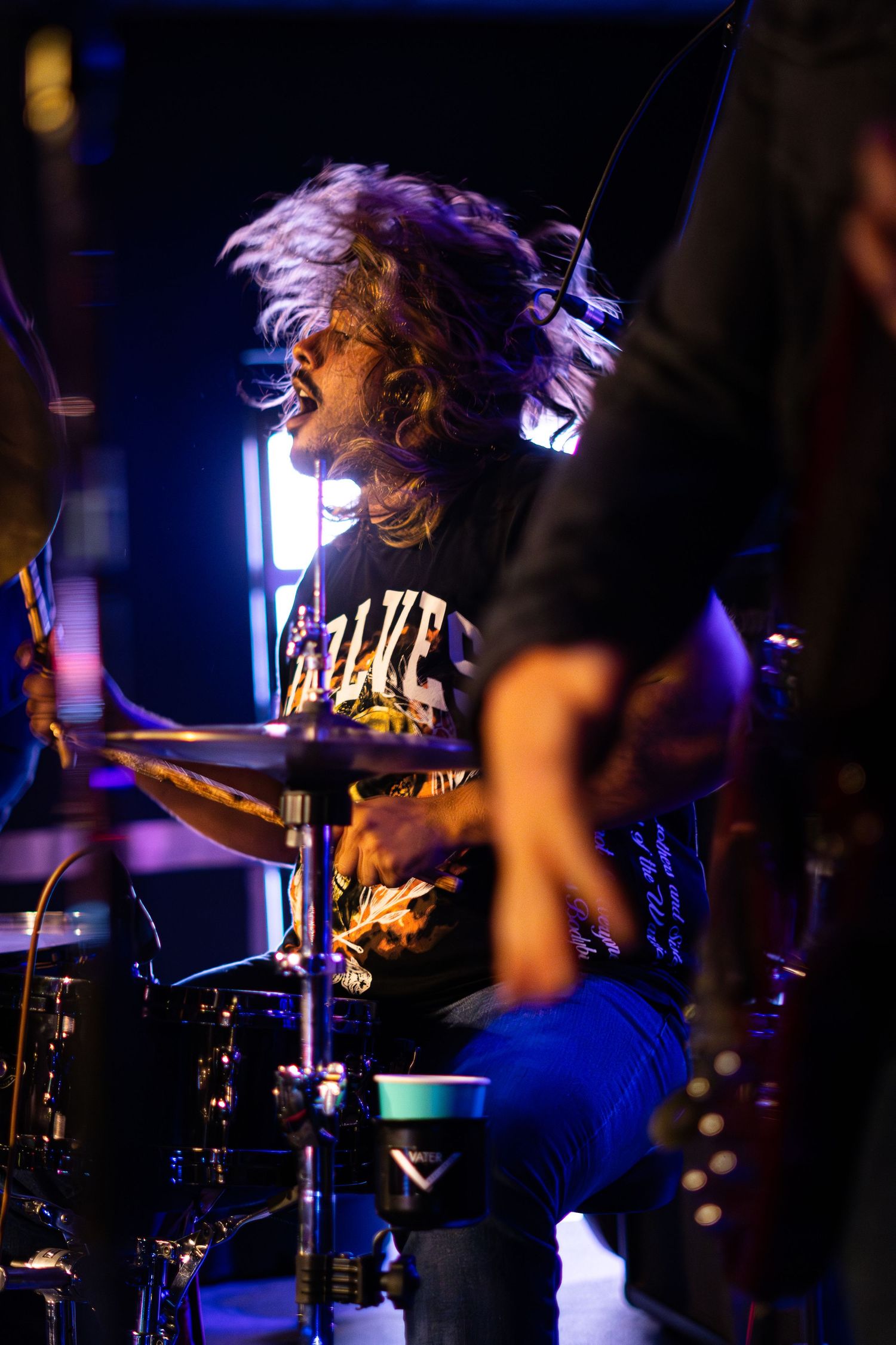 Drummer performs with hair flying during energetic live music performance.