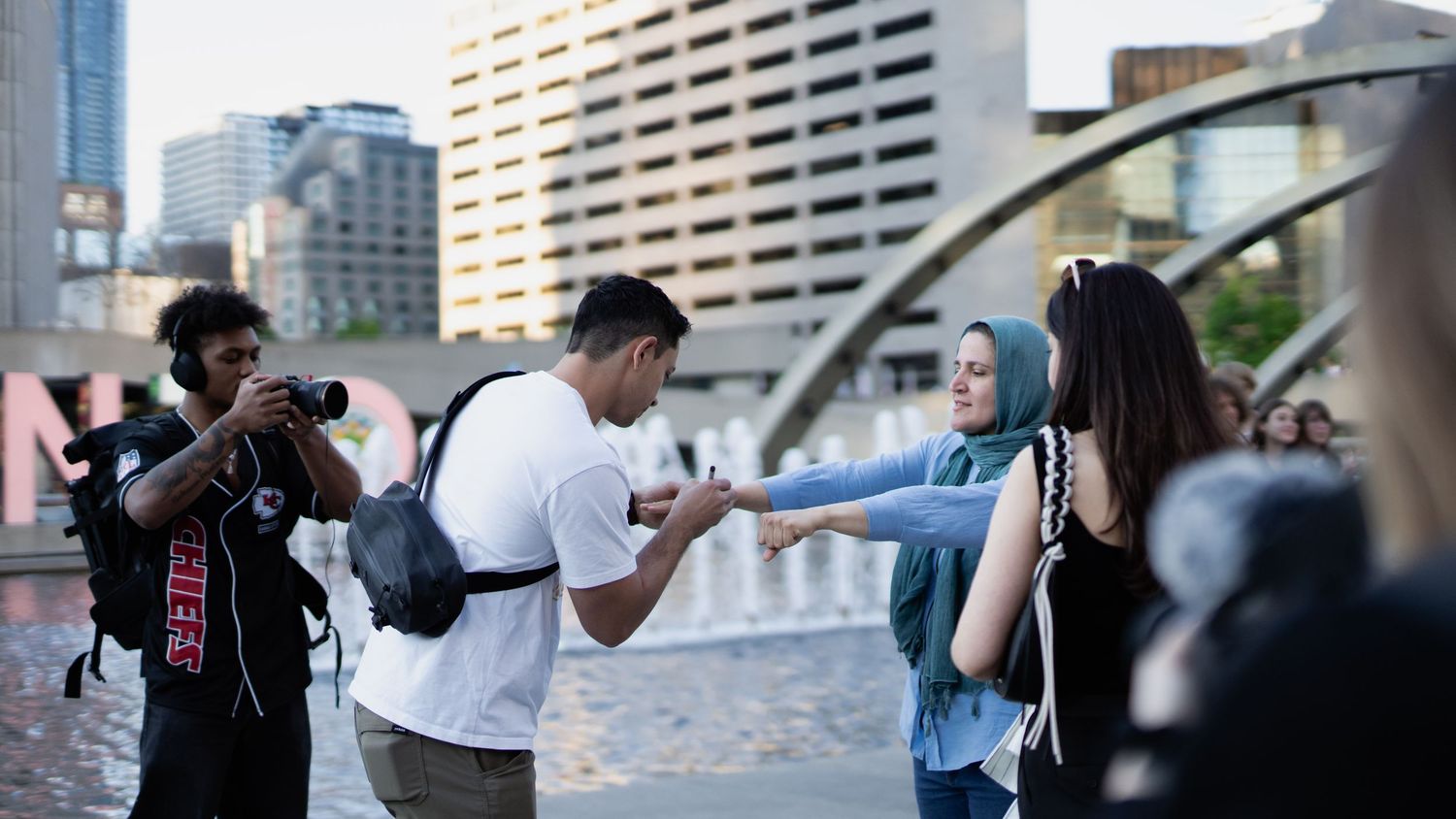 Urban cityscape with tall buildings and people gathering on a rooftop.