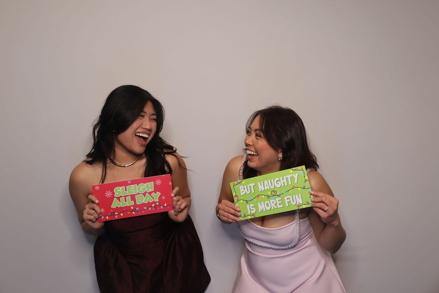 Best friends capturing fun memories at a photo booth with the grinch themed props