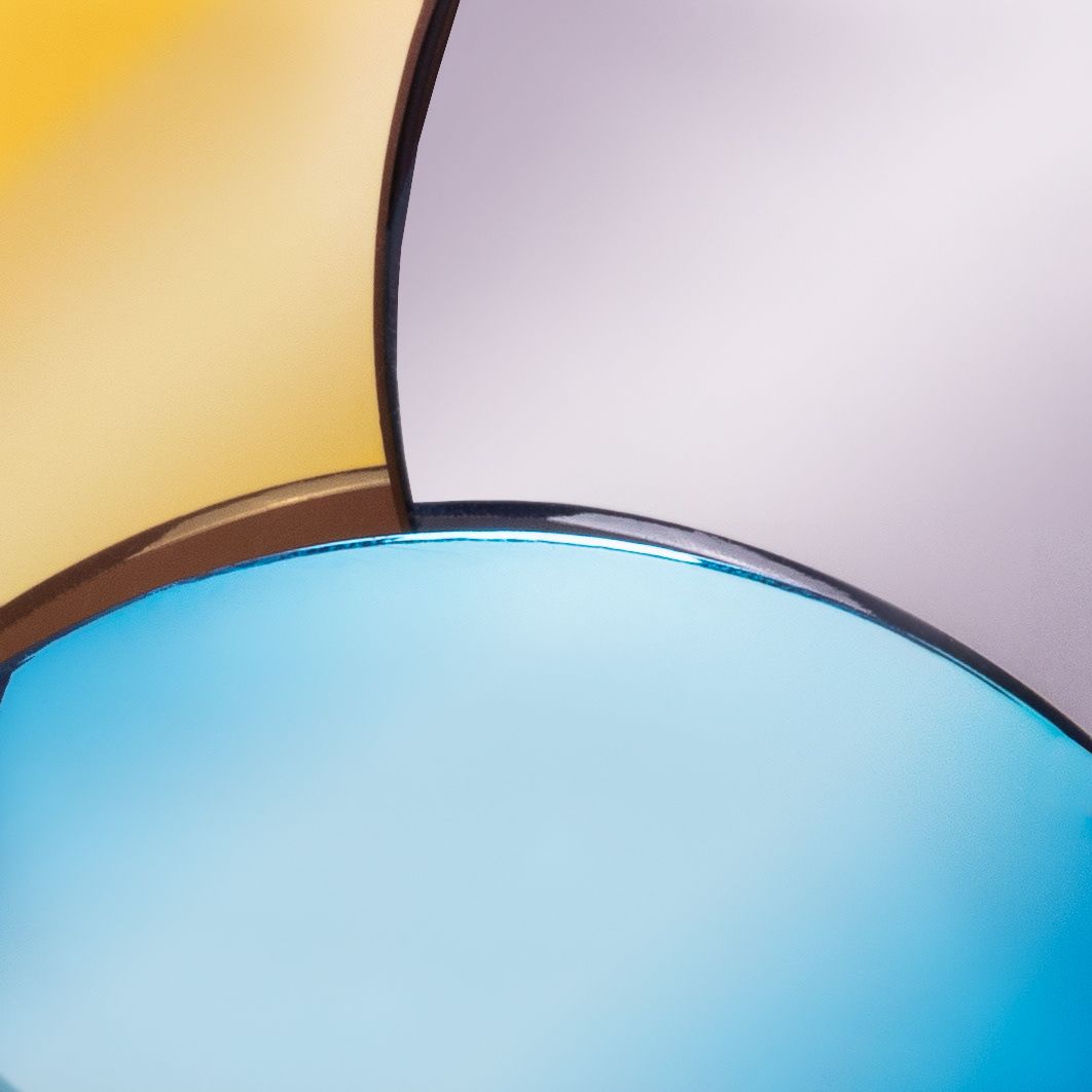 Close-up of overlapping round sunglass lenses in blue and lavender tints on yellow background.