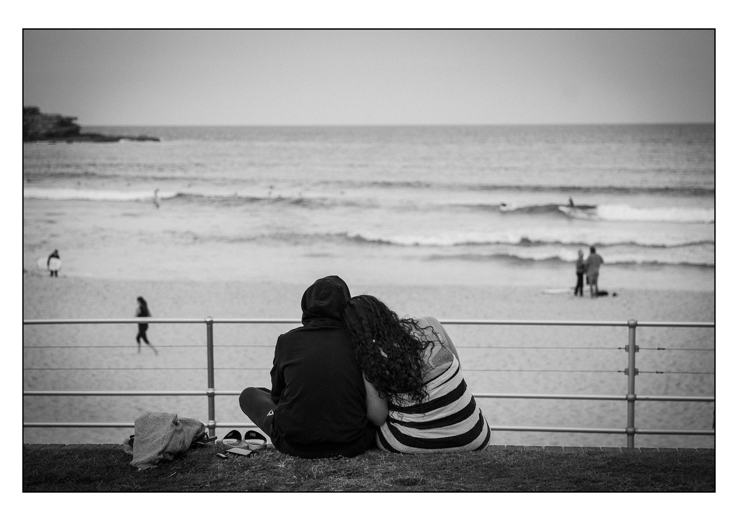 Couple sitting together watching ocean waves at the beach in black and white.