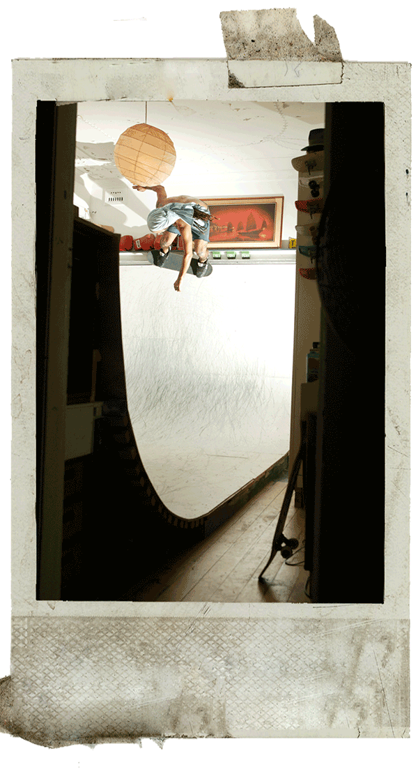 Skateboarder performing trick on indoor halfpipe ramp in polaroid frame.