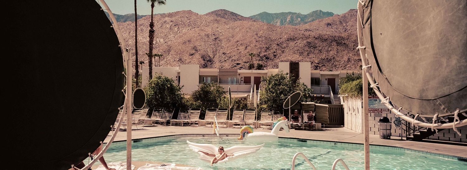 Luxury desert resort pool with mountain backdrop viewed through decorative circular frames.