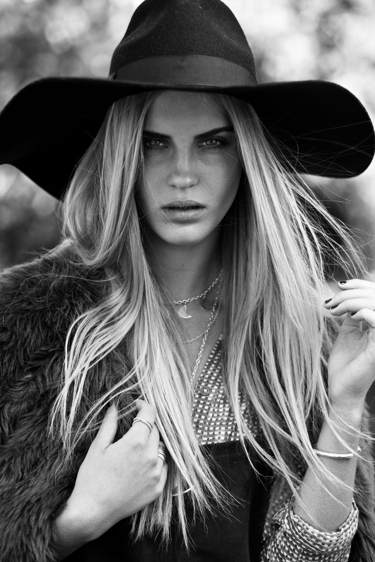 Black and white portrait of blonde woman in wide-brim hat and fur coat.