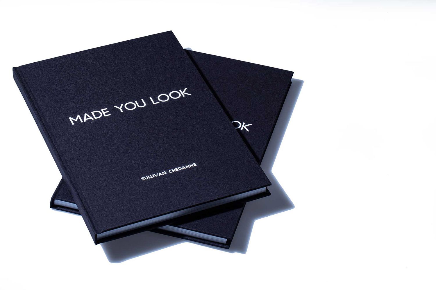 Two dark navy hardcover books titled MADE YOU LOOK by Sullivan Chedanne on white surface.