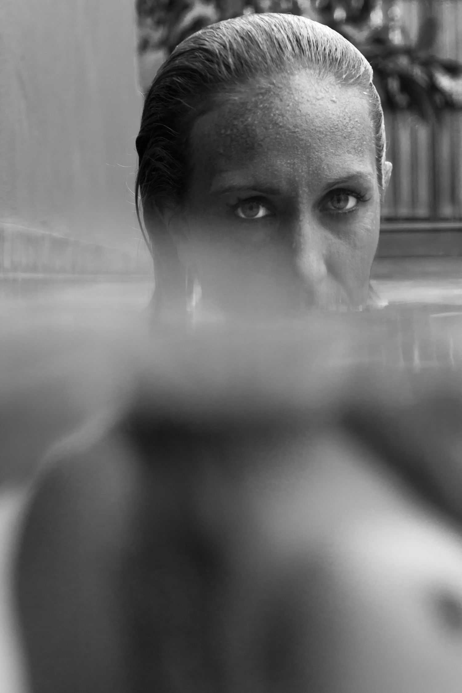 Close-up black and white portrait of a woman submerged to her nose in a pool.