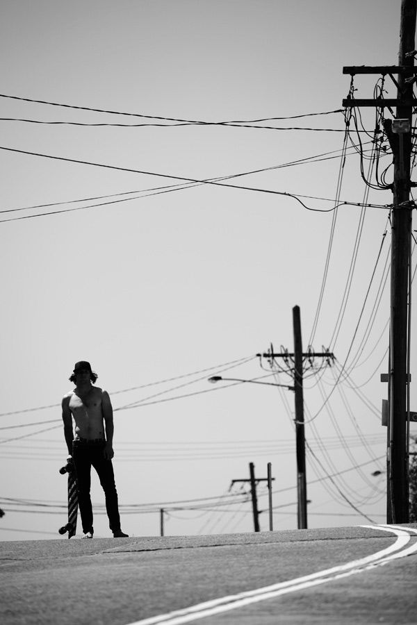 Silhouette of man standing on road with power lines against clear sky.