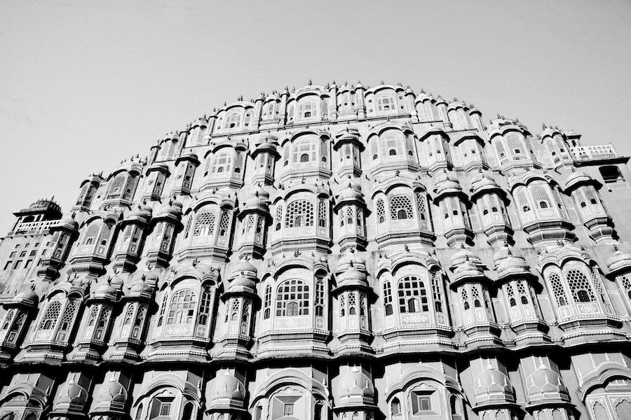 Black and white low angle view of the ornate facade of Hawa Mahal palace in Jaipur, India.