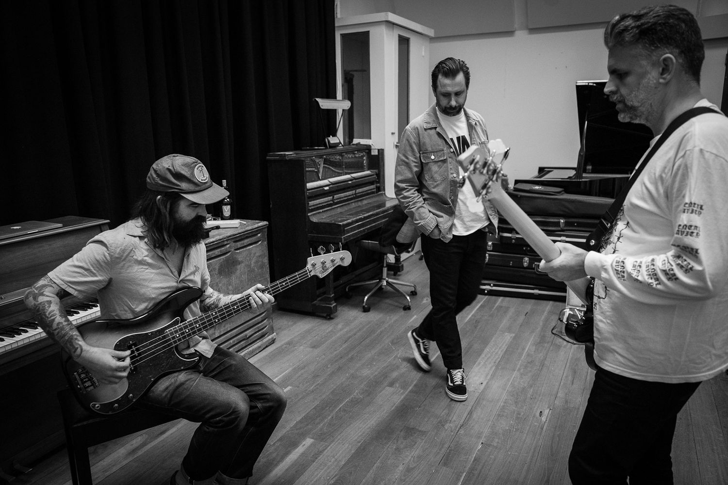 Three musicians jamming together in a black and white photo inside a recording studio.