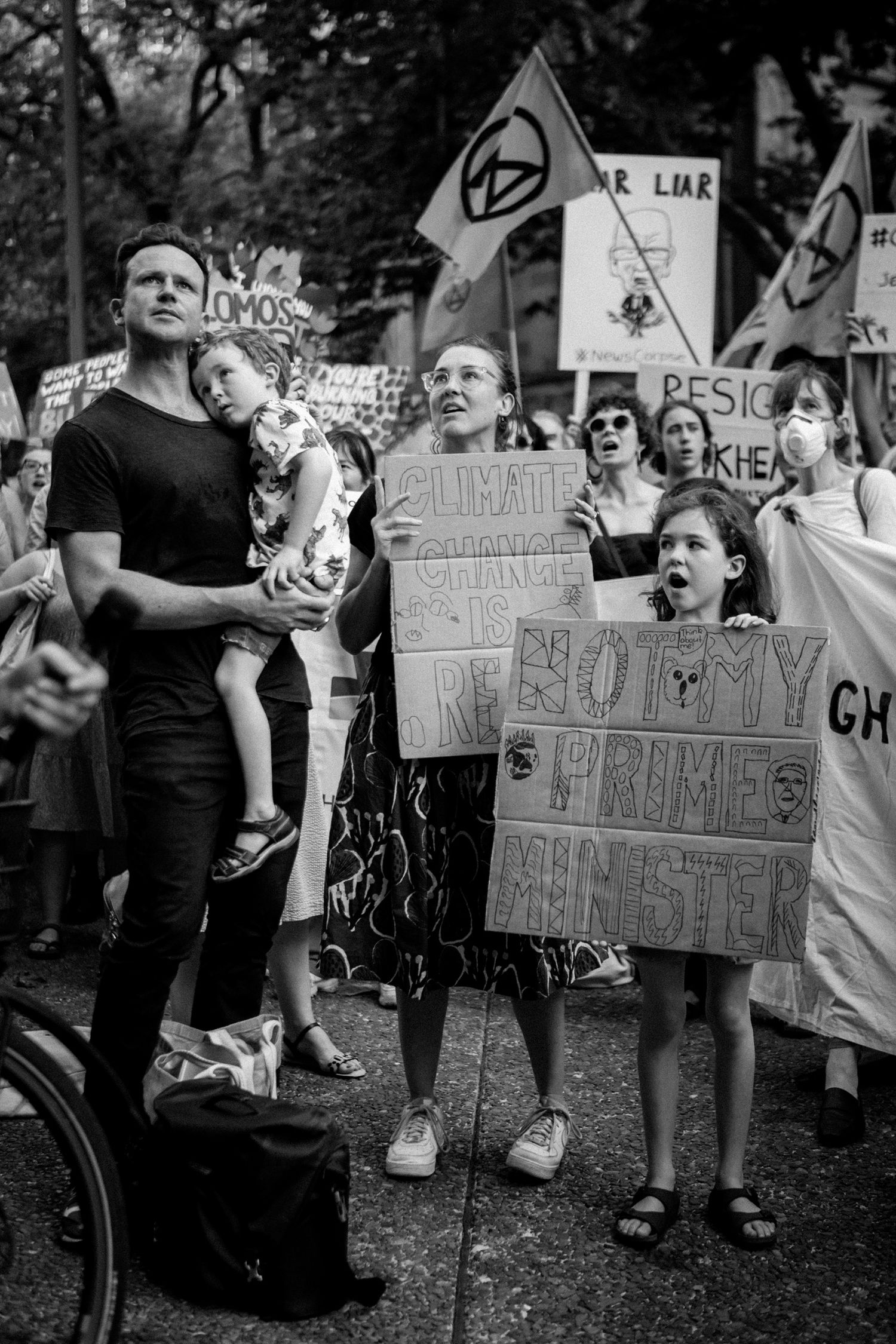 Black and white photo of protesters at a climate change rally holding signs in a crowd.