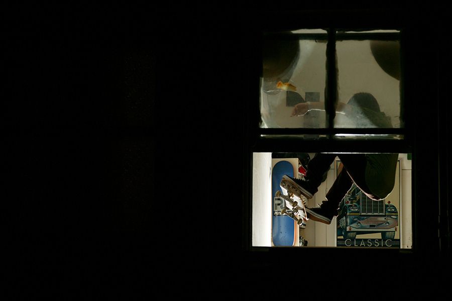 Person visible through a lit window at night working on a computer motherboard.