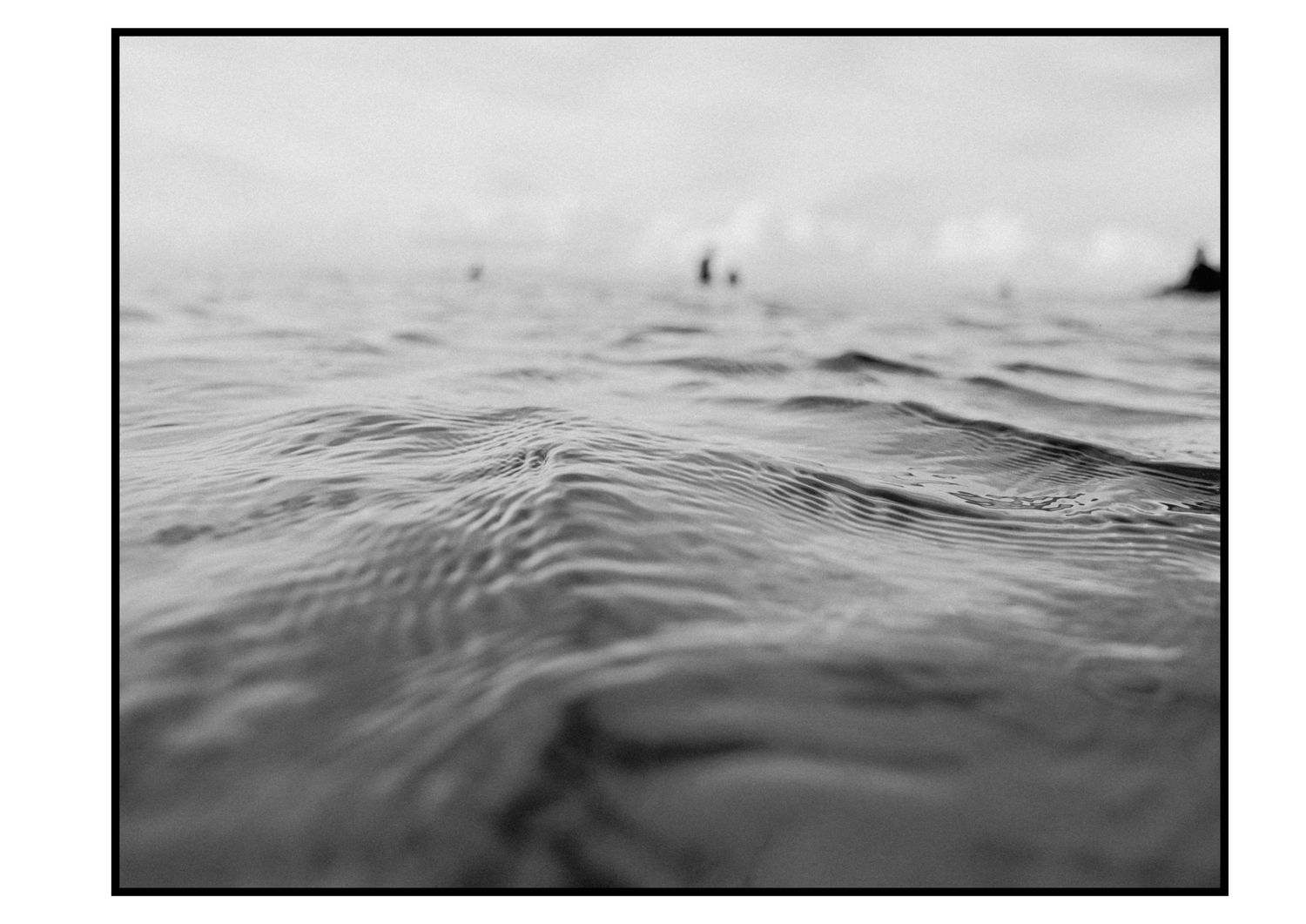 Close-up black and white photo of gentle ocean waves on a calm sea surface.