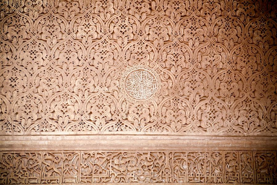 Intricate detailed Islamic geometric floral plasterwork carved into a pale beige decorative interior wall.