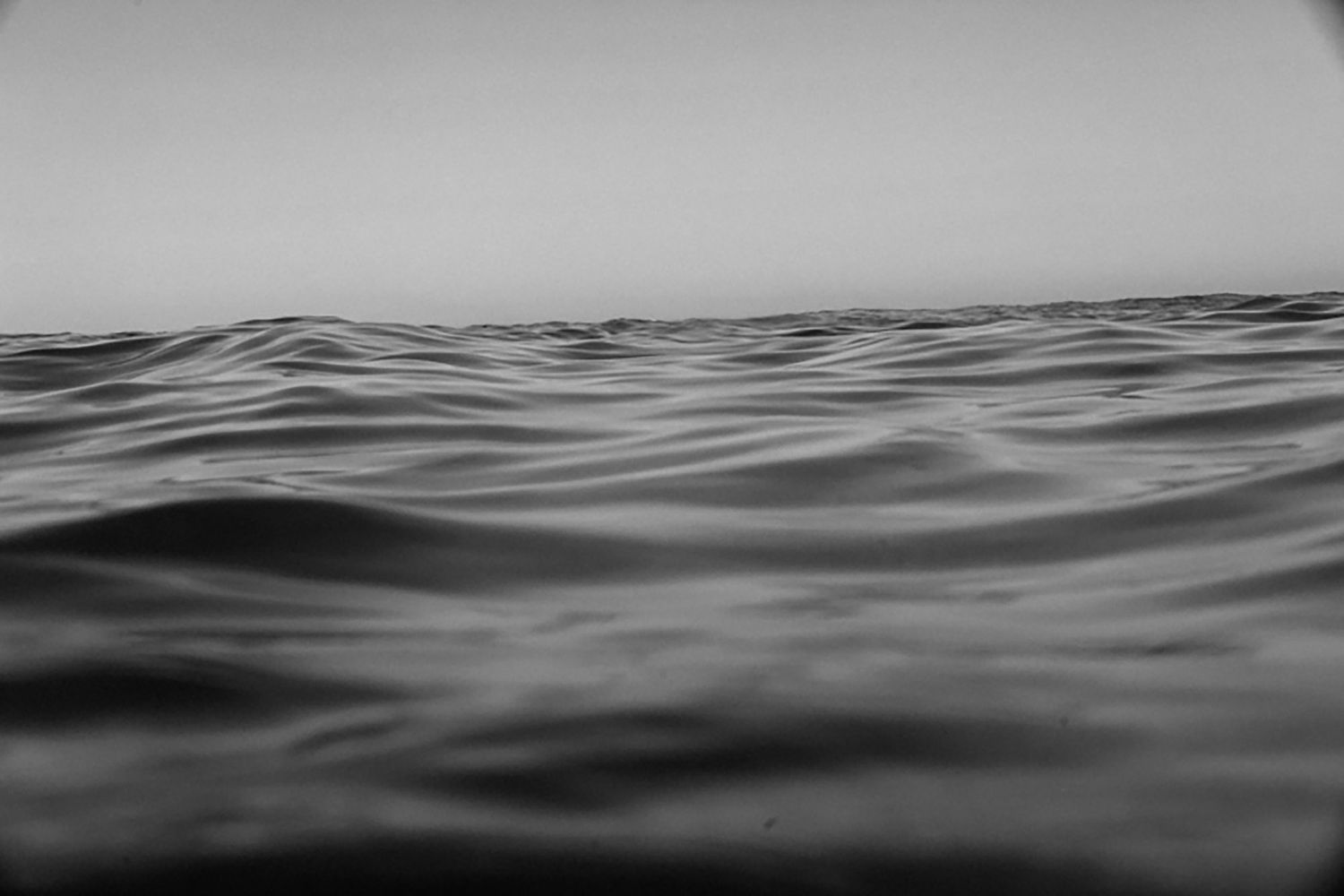 Black and white ocean waves with calm horizon, minimalist seascape photography.