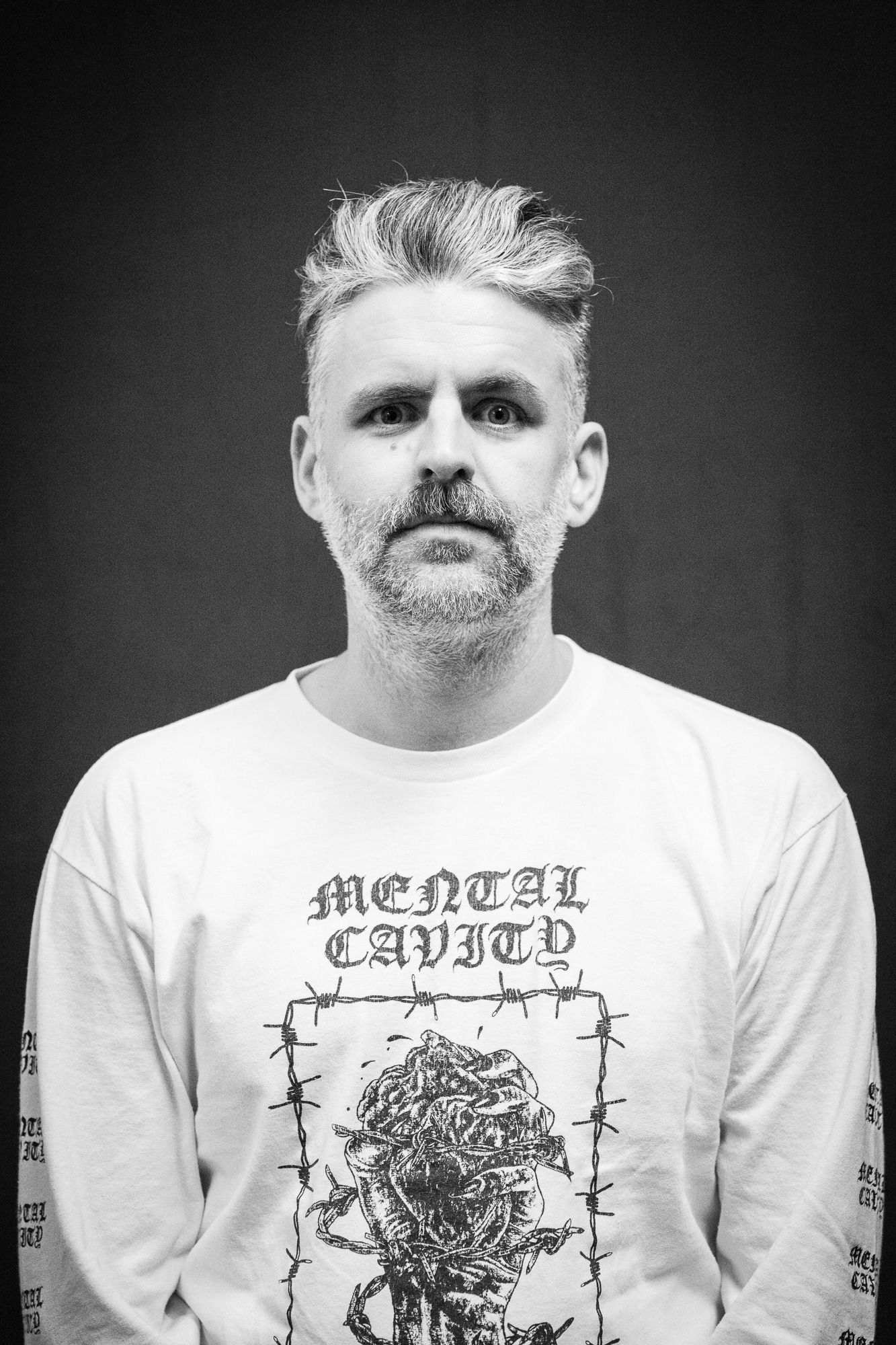 Black and white portrait of a middle-aged man wearing a Mental Cavity graphic tee.