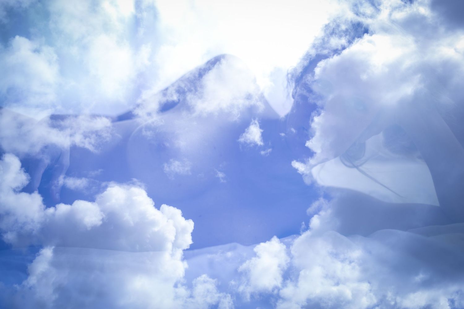 Bright blue sky with fluffy white clouds and sunlight breaking through in a geometric pattern.
