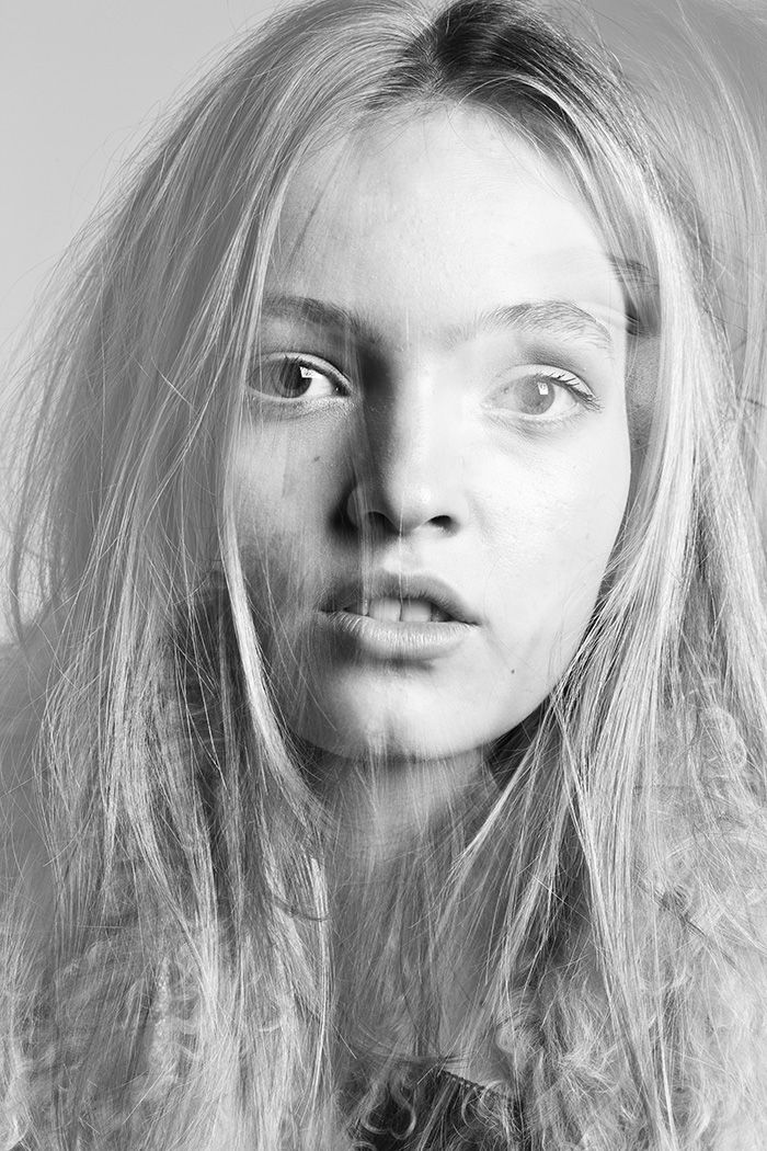 Black and white close-up portrait of a young blonde woman with flowing hair and freckles.