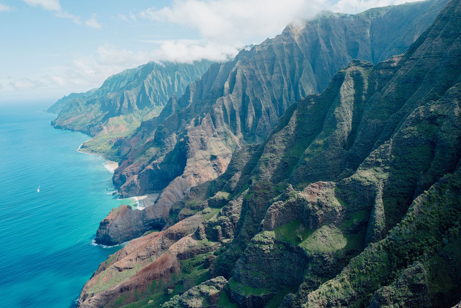 Aerial view of the dramatic Na Pali Coast cliffs and turquoise ocean in Kauai.