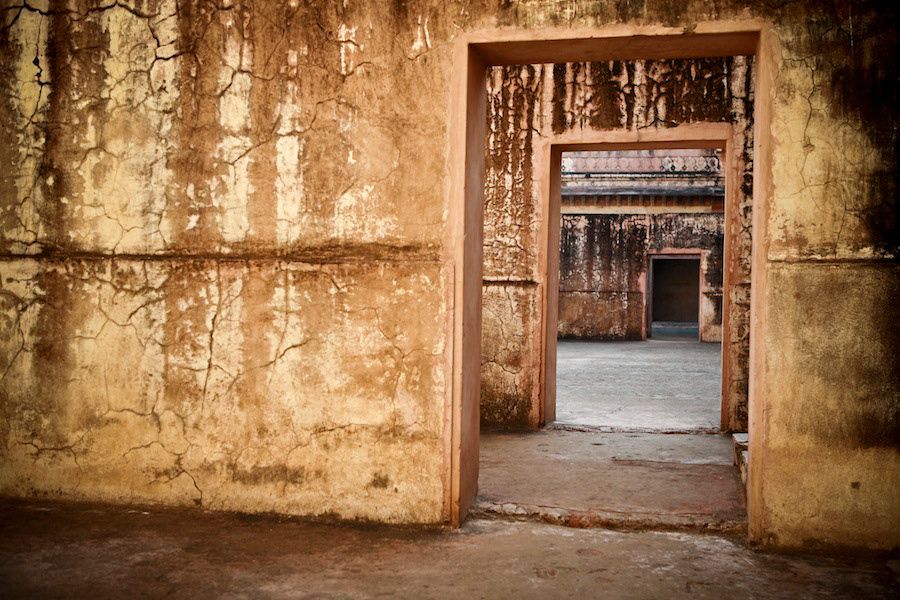 Ancient weathered doorways in a rustic Indian temple with crumbling ochre walls and layered archways.