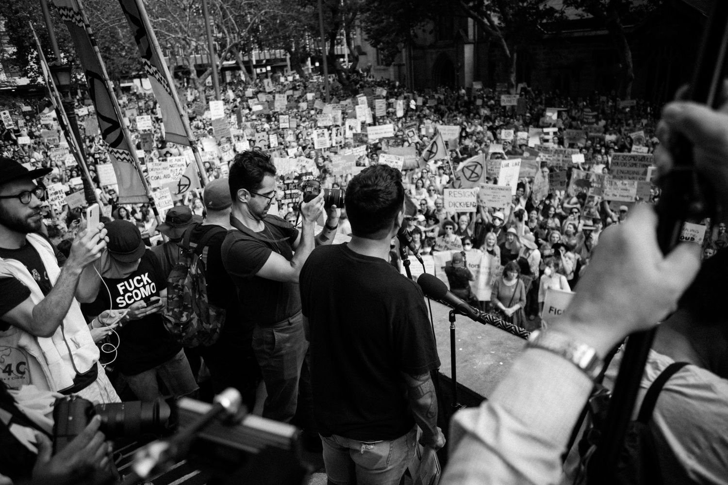 Black and white aerial view of large crowd at an outdoor protest rally.