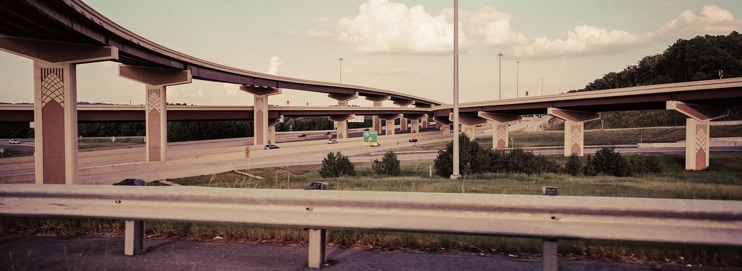 Panoramic view of a complex multi-level highway interchange with concrete overpasses and green median strips.