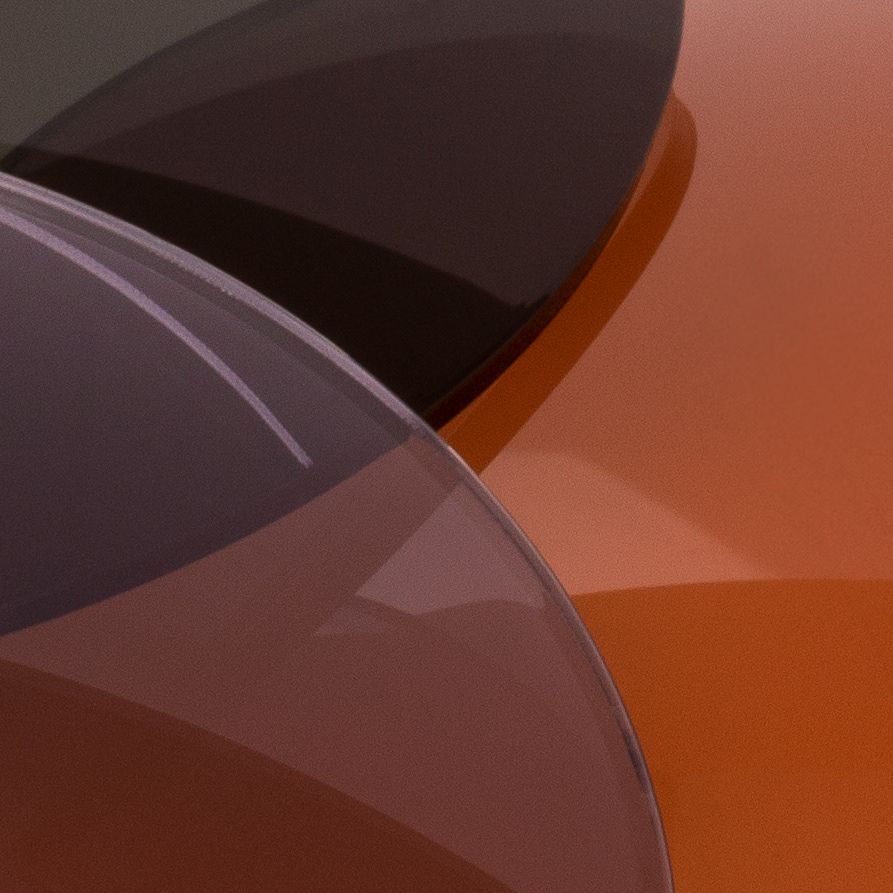 Close-up of overlapping orange and dark tinted circular sunglass lenses abstract detail.