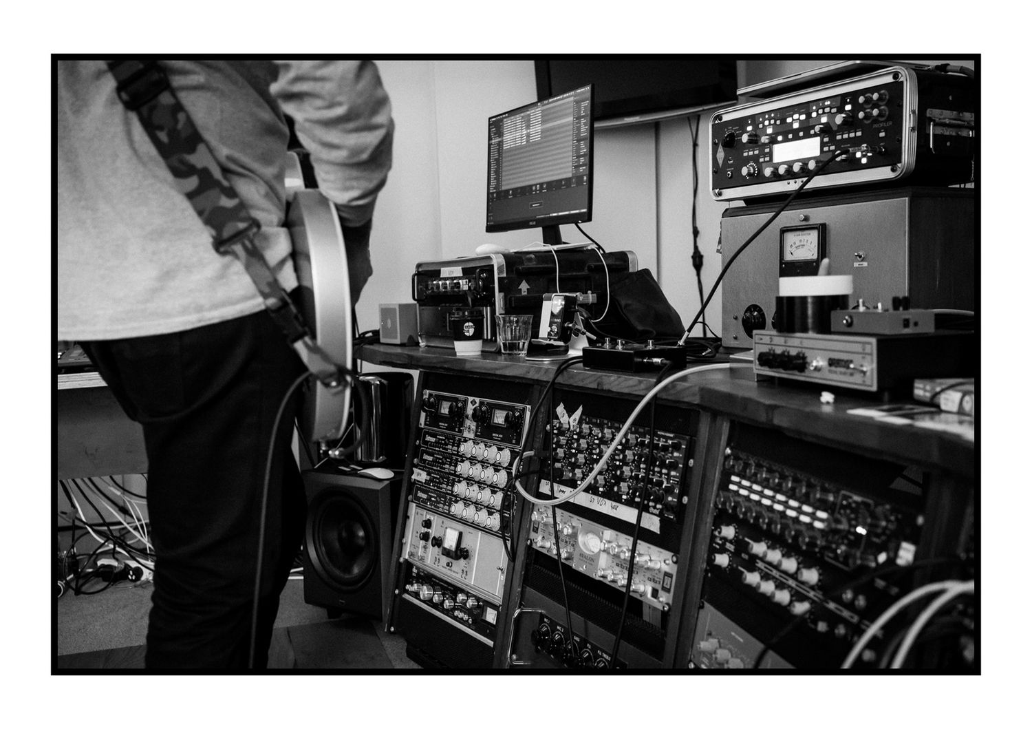 Black and white photo of professional audio mixing console with electronic music equipment.