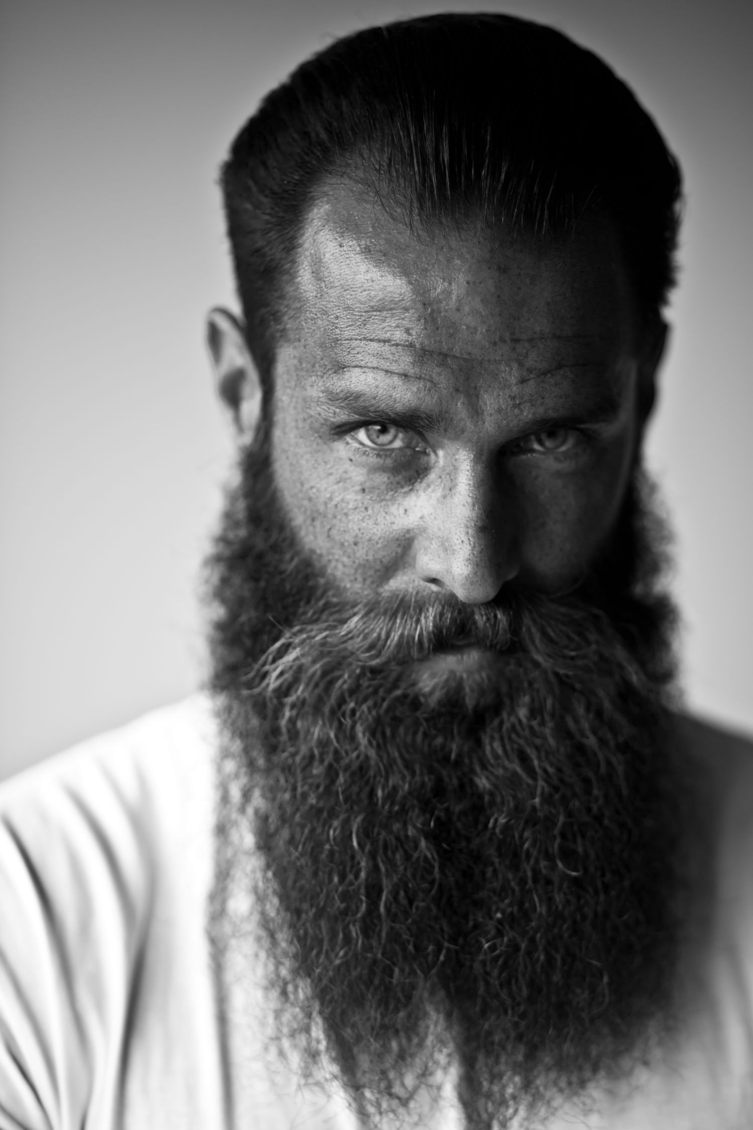 Intense black and white close-up portrait of a man with a long, full beard.