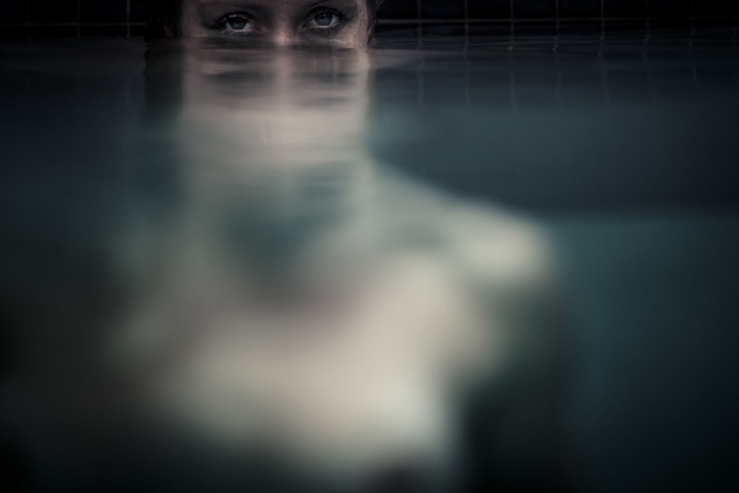 Mysterious close-up portrait of person partially submerged in water.