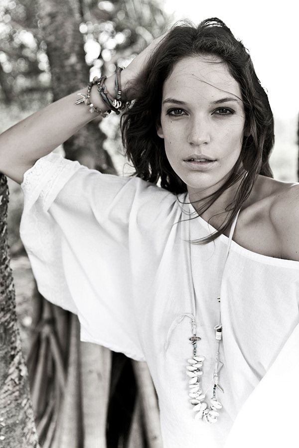 Black and white portrait of brunette woman in off-shoulder white top with jewelry.