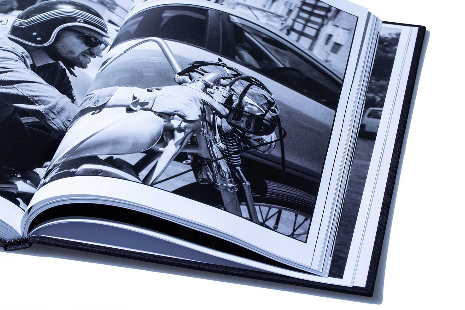 Open photography book showing black and white image of motorcycle and car on city street.