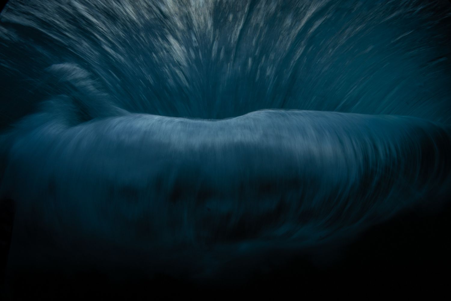 Dark dramatic underwater ocean wave abstract photography in deep blue.