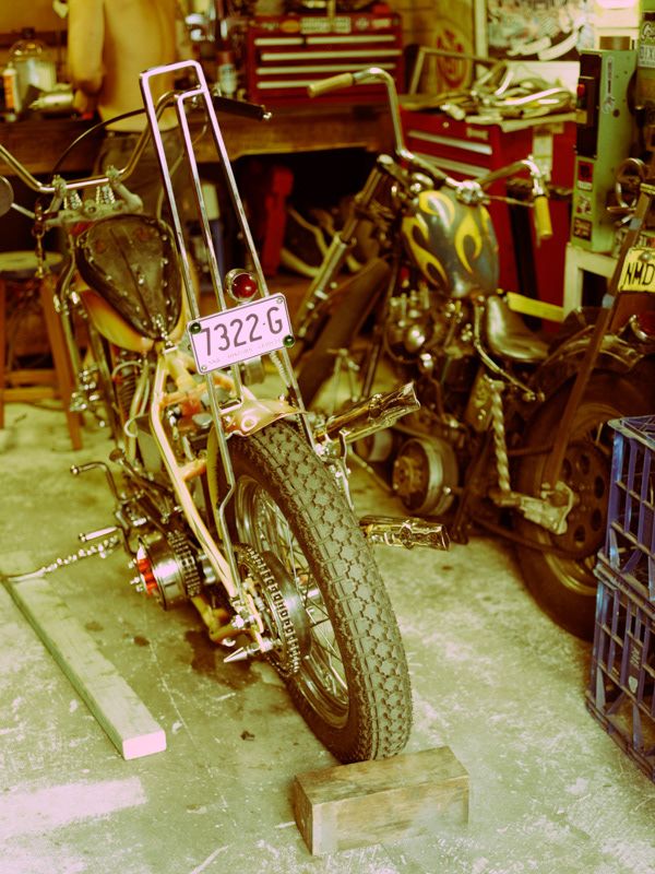 Vintage chopper motorcycle with license plate 7322G parked in a workshop garage.