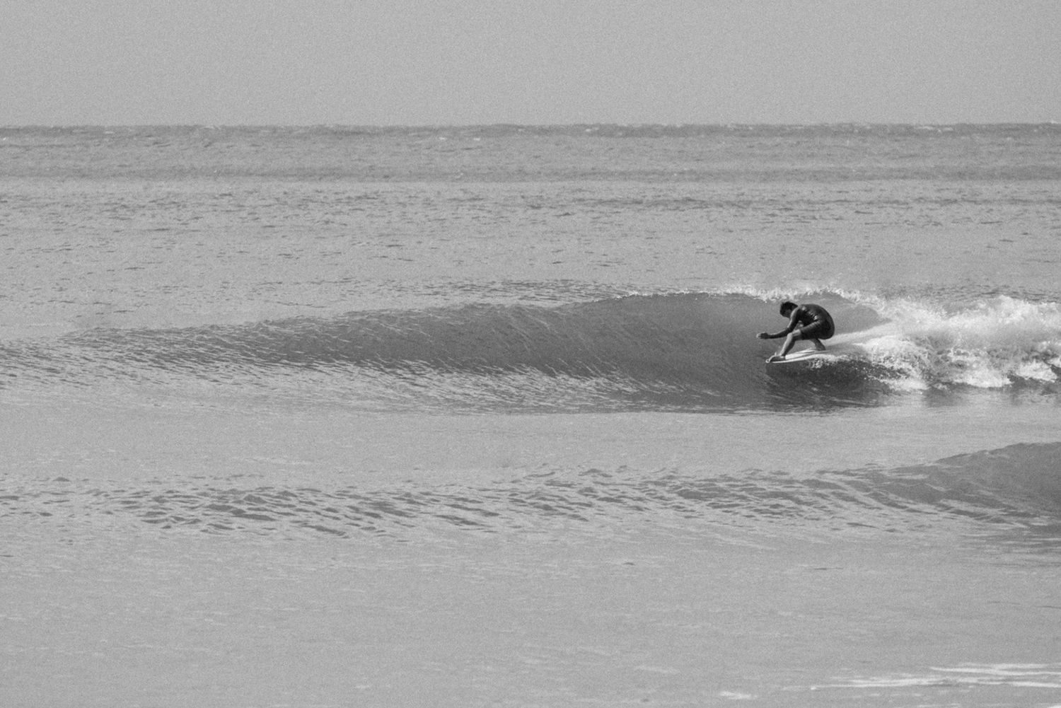 Black and white photo of a surfer riding a wave in the ocean.