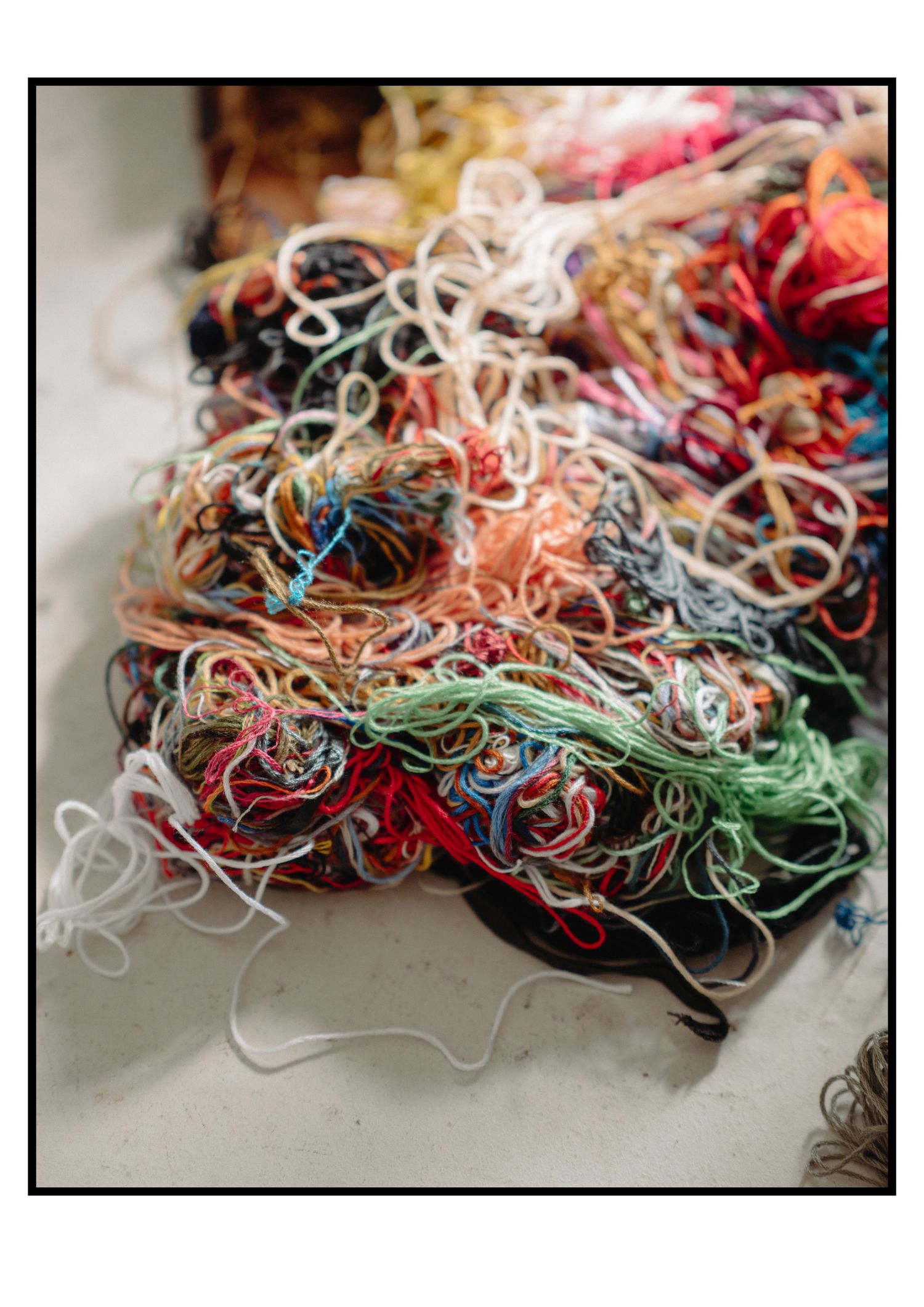 Colorful pile of tangled mixed fabric ribbons and trims on white surface.